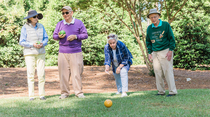 Group of senior friends lawn bowling on a sunny day