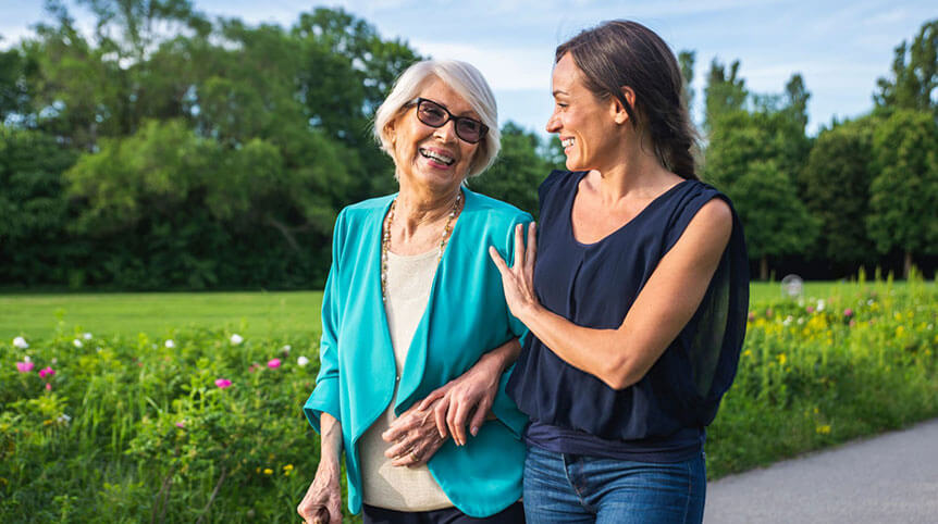 Caring mid-adult woman with senior woman walking in park
